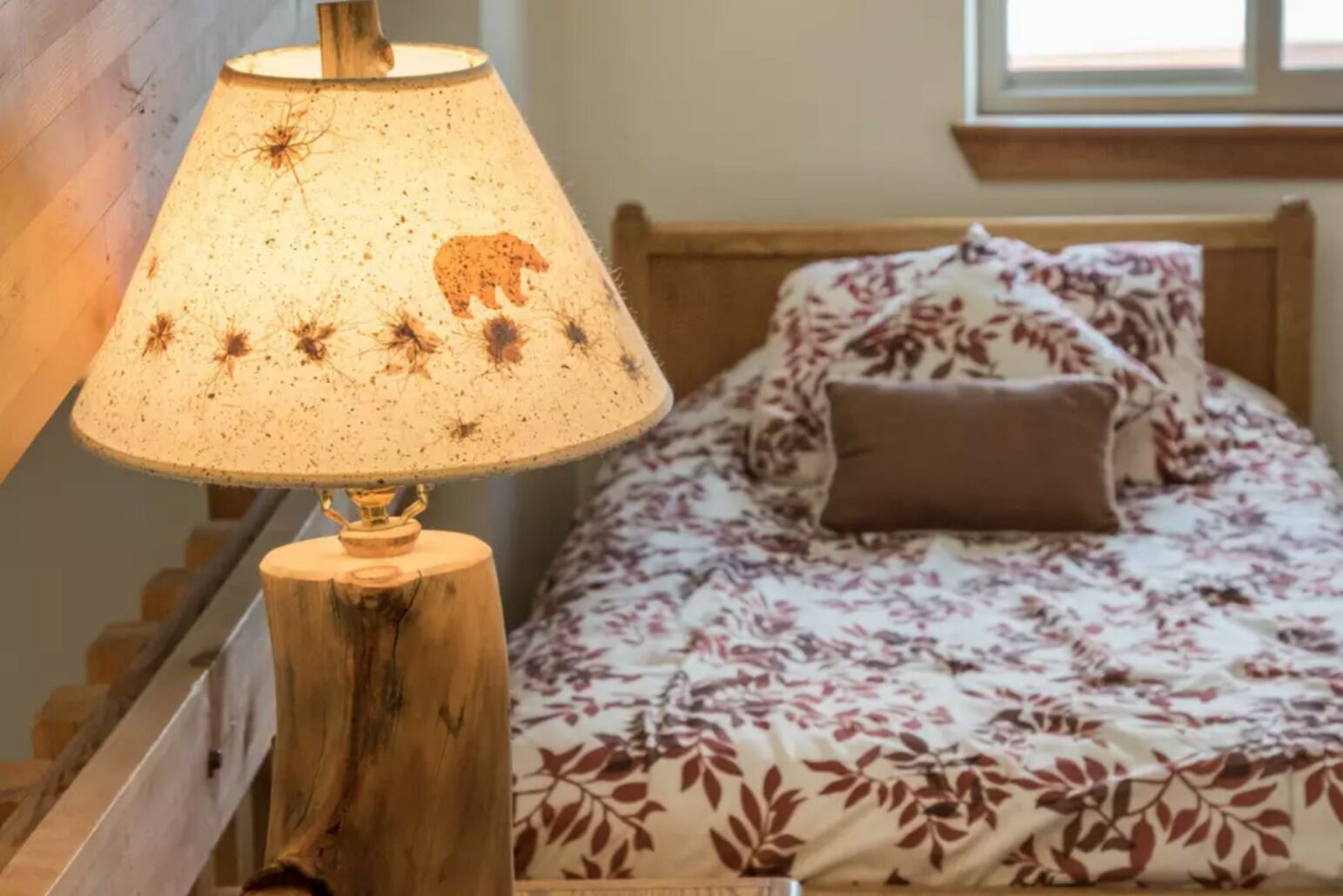 A bed with a floral-patterned bedspread and a wooden headboard.