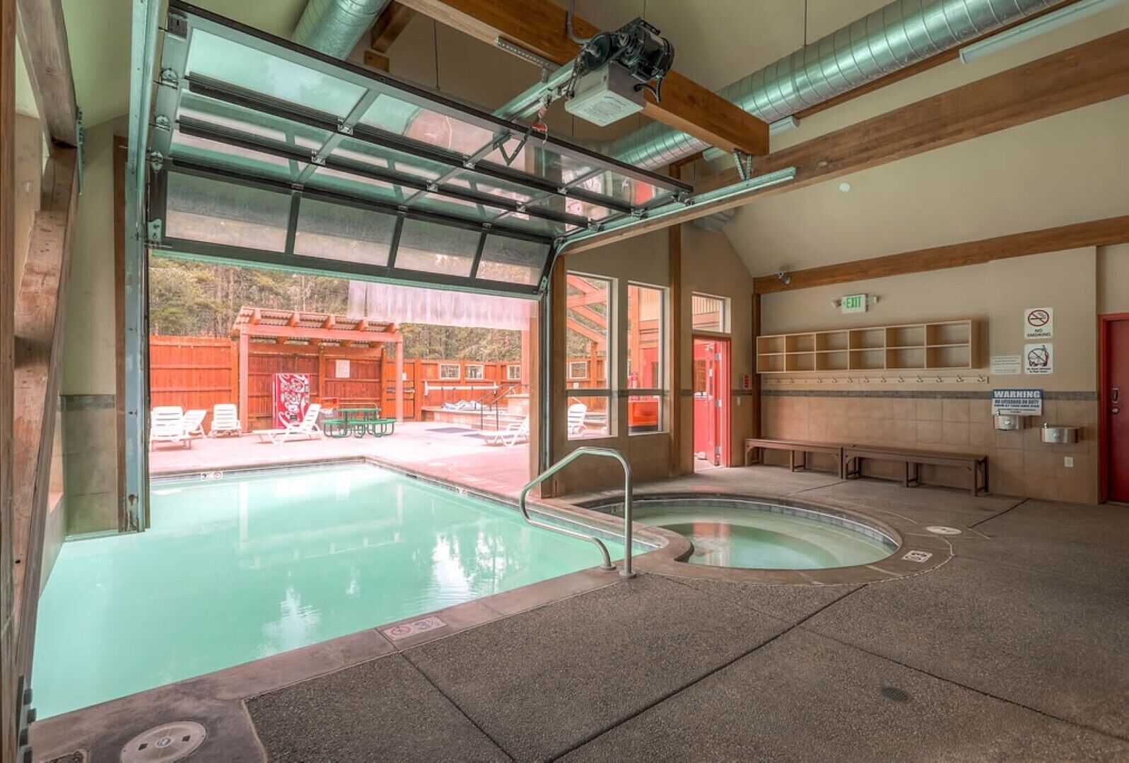 Une piscine intérieure dotée d’une paroi vitrée, un espace sauna et un coin salon avec des bancs.