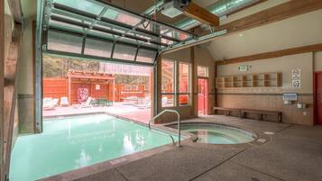 Une piscine intérieure dotée d’une paroi vitrée, un espace sauna et un coin salon avec des bancs.