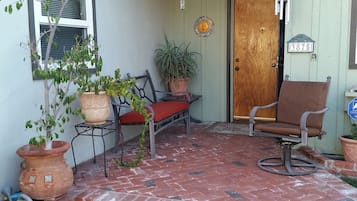 Step out onto the porch and enjoy the tranquil atmosphere, where you can sit in one of two comfortable chairs with a potted plant nearby.