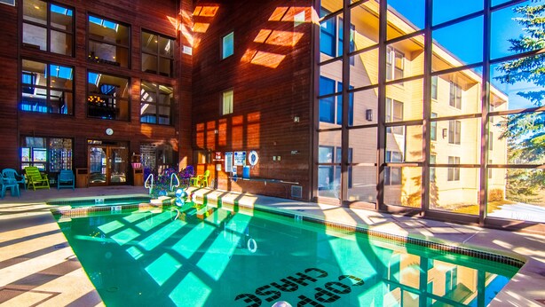 A pool area with a view of a building with large windows and a wooden facade.