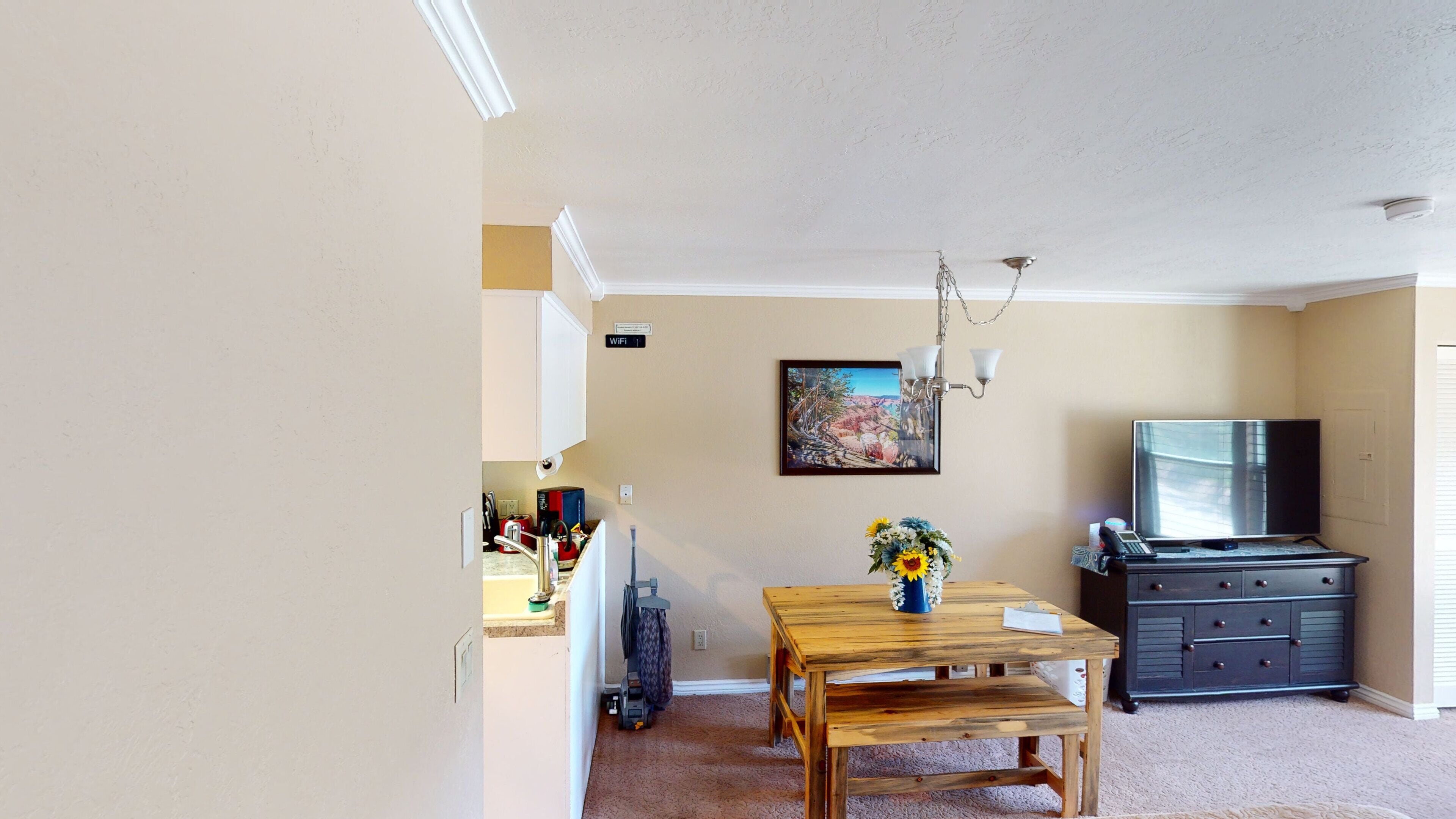 Ein Wohnzimmer mit einem Holztisch, einem Fernseher und einem Gemälde an der Wand.