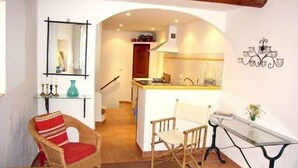 A cozy living area with a wicker chair, a small table, and a mirror on the wall. - Charming Village House In Medieval Village, Close To Beach And Nice (Cagnes-Sur-Mer)