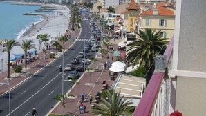 A coastal street with buildings, a beach, and a clock tower. - Charming Village House In Medieval Village, Close To Beach And Nice (Cagnes-Sur-Mer)