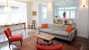 A living room with a sofa, chairs, a coffee table, and a dining area with chairs and a table. - Modern Farmhouse in Historic Downtown Bozeman (Bozeman)