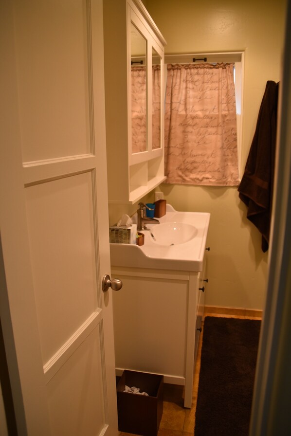 Une salle de bain avec un lavabo blanc, un miroir et un rideau de douche.