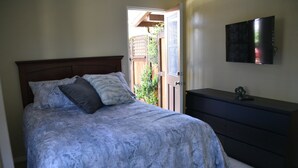 Un dormitorio con cama, cómoda y televisor montado en la pared.