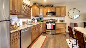 A modern kitchen with wooden cabinets, stainless steel appliances, and a clock on the wall.