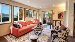 A spacious living room with a red sofa, a round coffee table, and a cow print armchair.