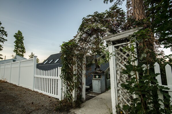 A white picket fence, a wooden arbor with climbing plants, and a small shed with the number 510 visible. - Lakefront Home With Hot Tub, Dock, Great Views From The Living Room & Bedrooms (Somers)