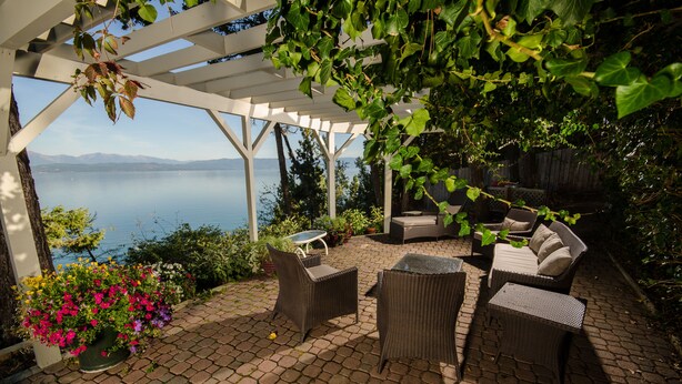 A covered patio with wicker furniture, a potted plant, and a view of the lake. - Lakefront Home With Hot Tub, Dock, Great Views From The Living Room & Bedrooms  (Somers)