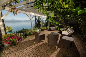 A covered patio with wicker furniture, a potted plant, and a view of the lake. - Lakefront Home With Hot Tub, Dock, Great Views From The Living Room & Bedrooms (Somers)