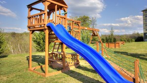 Eine Holzspielanlage mit einer blauen Rutsche und Seilnetz.
