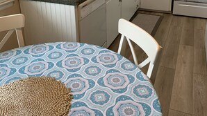 A compact kitchen with white cabinets, a sink, and a stove. There's a patterned tablecloth on a round table.