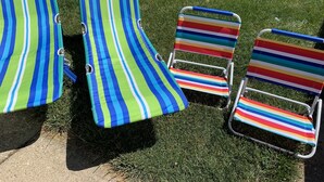 Three striped beach chairs on a grassy lawn.