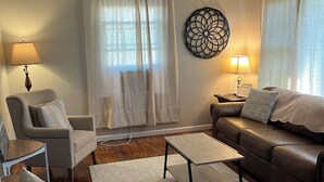 A living room with a sofa, armchair, coffee table, and two lamps.