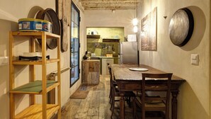 A rustic kitchen with wooden shelves, a dining table, and a refrigerator. - CHARMING HIDEAWAY IN FLORENCE OLD TOWN (Firenze)
