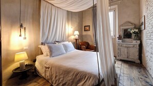 Une chambre à coucher avec un grand lit, une table de chevet avec une lampe, une chaise, un miroir et une armoire.