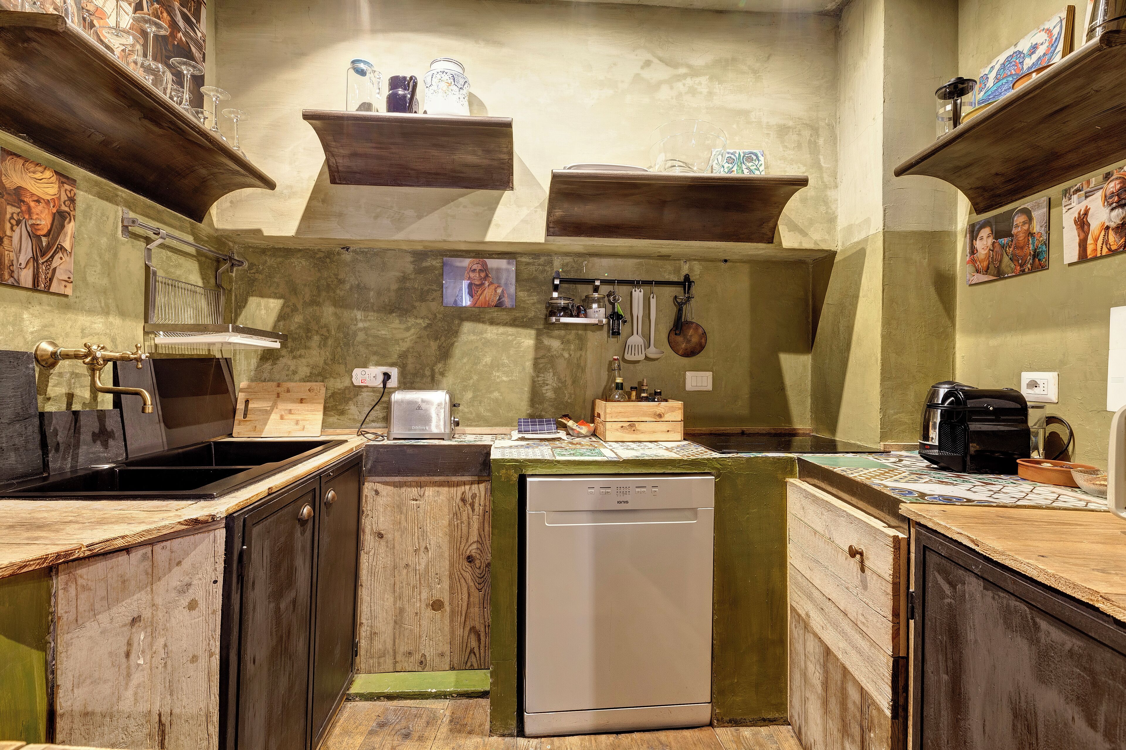 Une cuisine de taille réduite, dotée de meubles en bois, d’un lave-vaisselle et de divers ustensiles de cuisine.