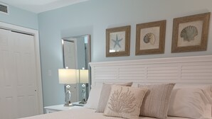 A neatly made bed with a textured blanket, a bedside table with a lamp, and framed wall art.