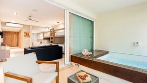Un interior moderno con una zona de estar, una bañera acristalada y una cocina visible al fondo.