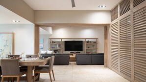 Una sala de estar moderna con comedor, televisor de pantalla plana y ventilador de techo.