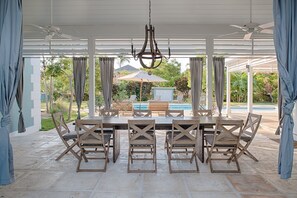 Un espacio de comedor al aire libre cubierto con una piscina al fondo.