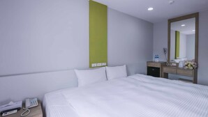 Una habitación de hotel con cama, mesita de noche, teléfono y espejo.