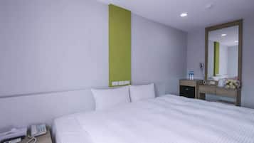A hotel room with a bed, bedside table, phone, and a mirror.