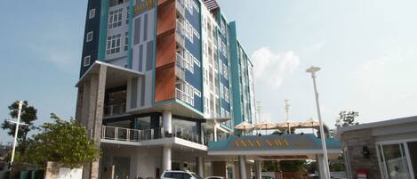 A multi-story hotel with a modern design, featuring balconies and a prominent entrance with signage.