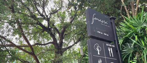 A sign for 'Foreste' cafe with operating hours and amenities including free wifi, food, and a coffee symbol.