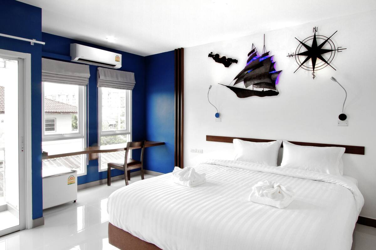 Una habitación de hotel moderna con una cama grande, un escritorio y una ventana con vistas a edificios.