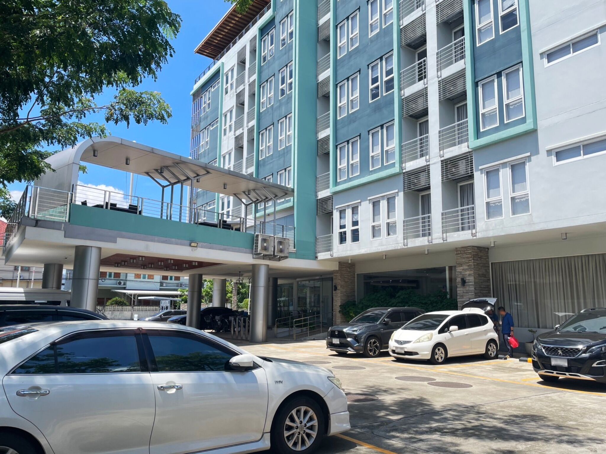 A multi-story building with a covered walkway and parking area.