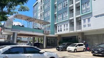 A multi-story building with a covered walkway and parking area.