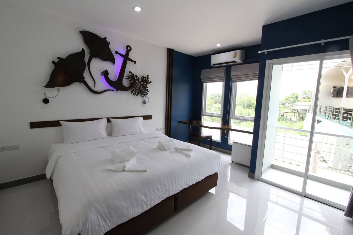 Una habitación de hotel moderna con una cama grande, un elemento decorativo en la pared, una ventana con vistas y un equipo de aire acondicionado.