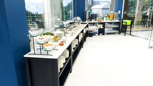 Un buffet con diversi alimenti e utensili, vetrine in vetro e un interno moderno con pareti blu e ampie finestre.