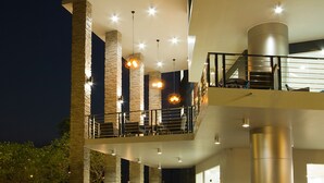 Un edificio a più livelli con un balcone, colonne in pietra e luci pensili.