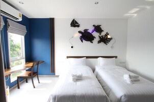 A hotel room with two beds, a desk, and a window with blinds.