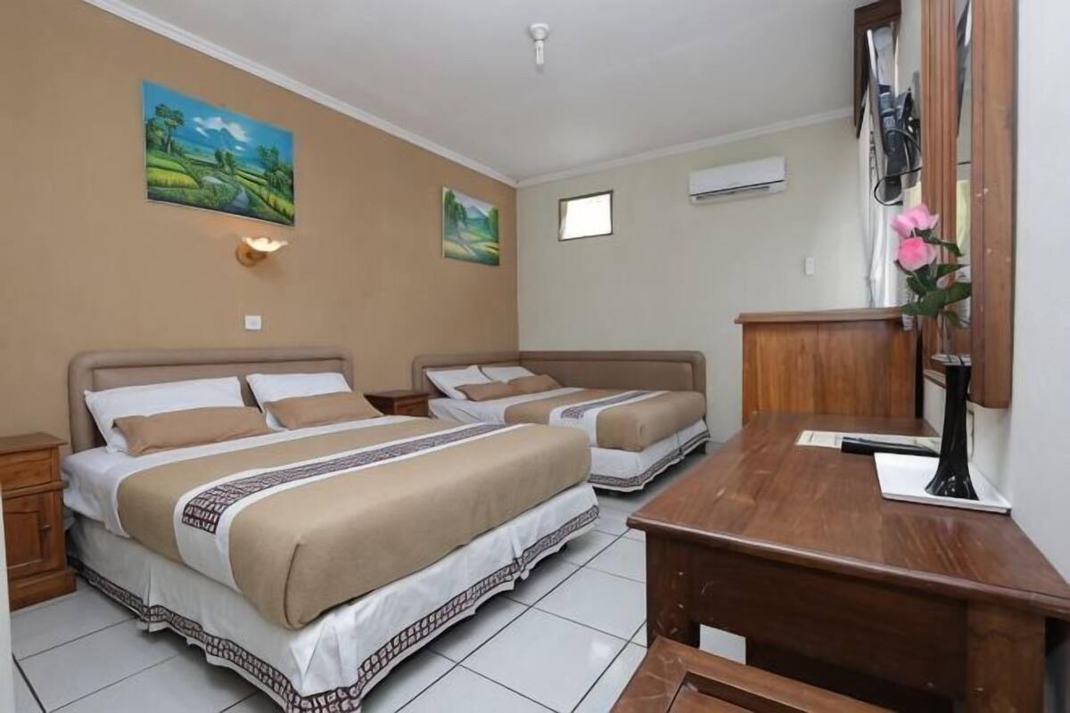 Een hotelkamer met twee bedden, een houten bureau, een spiegel en twee aan de muur bevestigde schilderijen.