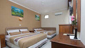 Ein Hotelzimmer mit zwei Betten, einem Holztisch, einem Spiegel und einem Bild an der Wand.