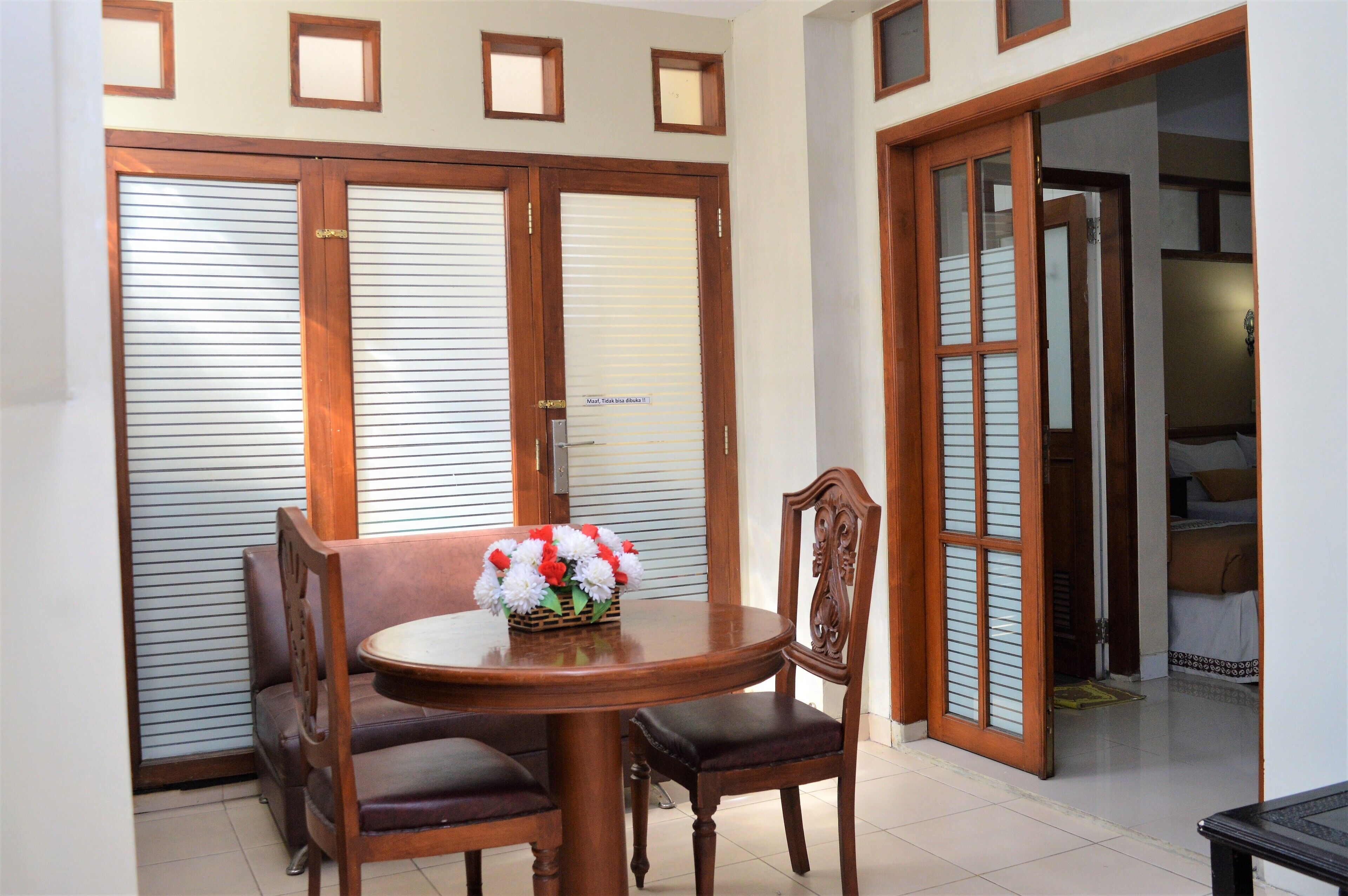 A dining area with a wooden table and chairs, a basket of flowers, and a sliding door with a sign.