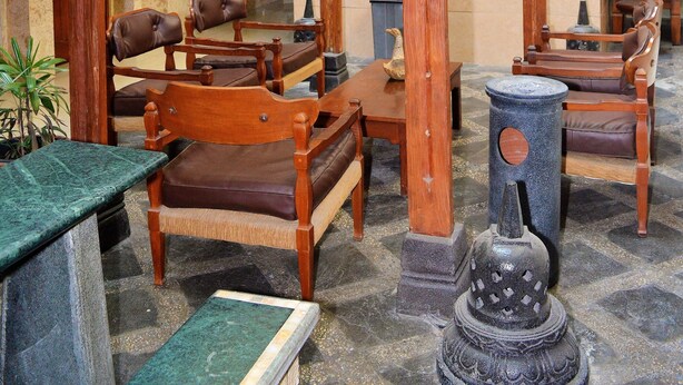 A traditional wooden structure with seating, a stone pillar, and a framed picture on the wall. - Hotel Mataram 2 Malioboro (Yogyakarta)