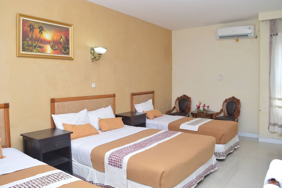 Une chambre d’hôtel avec trois lits, un tableau au mur, une table de chevet, un appareil de climatisation et une fenêtre avec des rideaux.