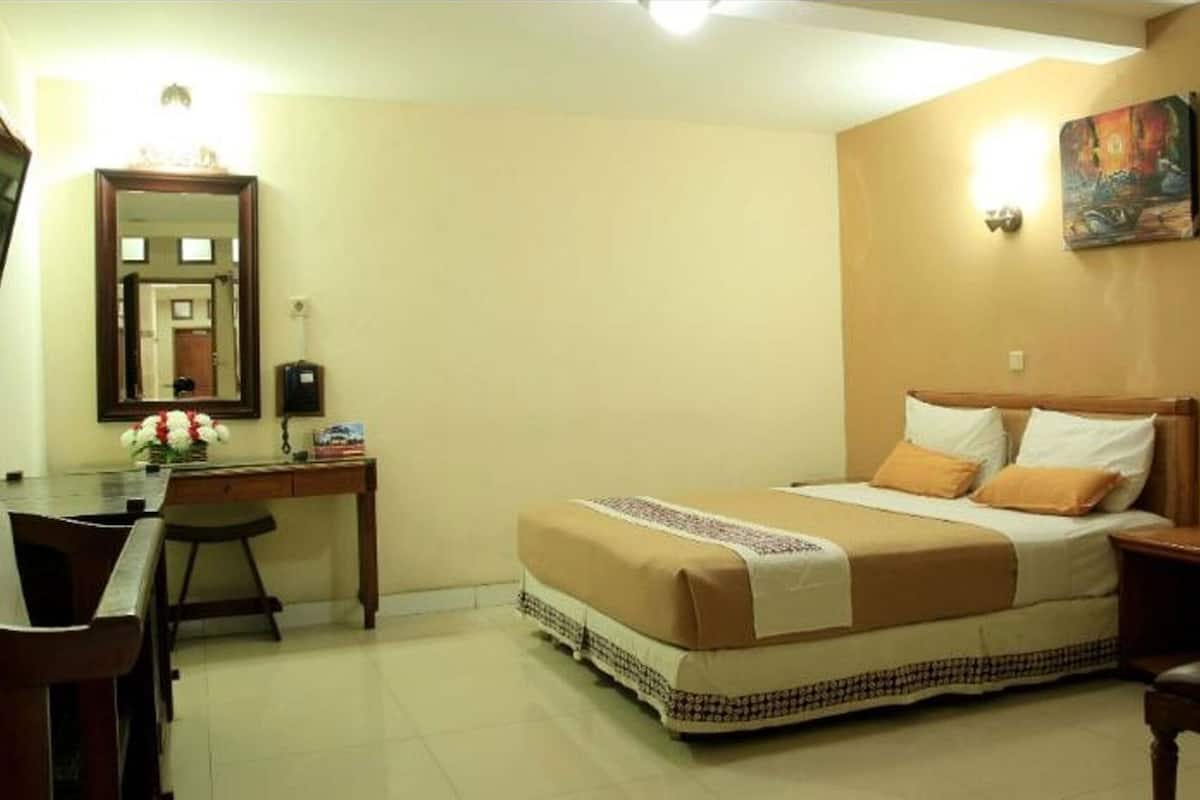 Une chambre d’hôtel avec un lit, un bureau, une chaise et un tableau au mur.