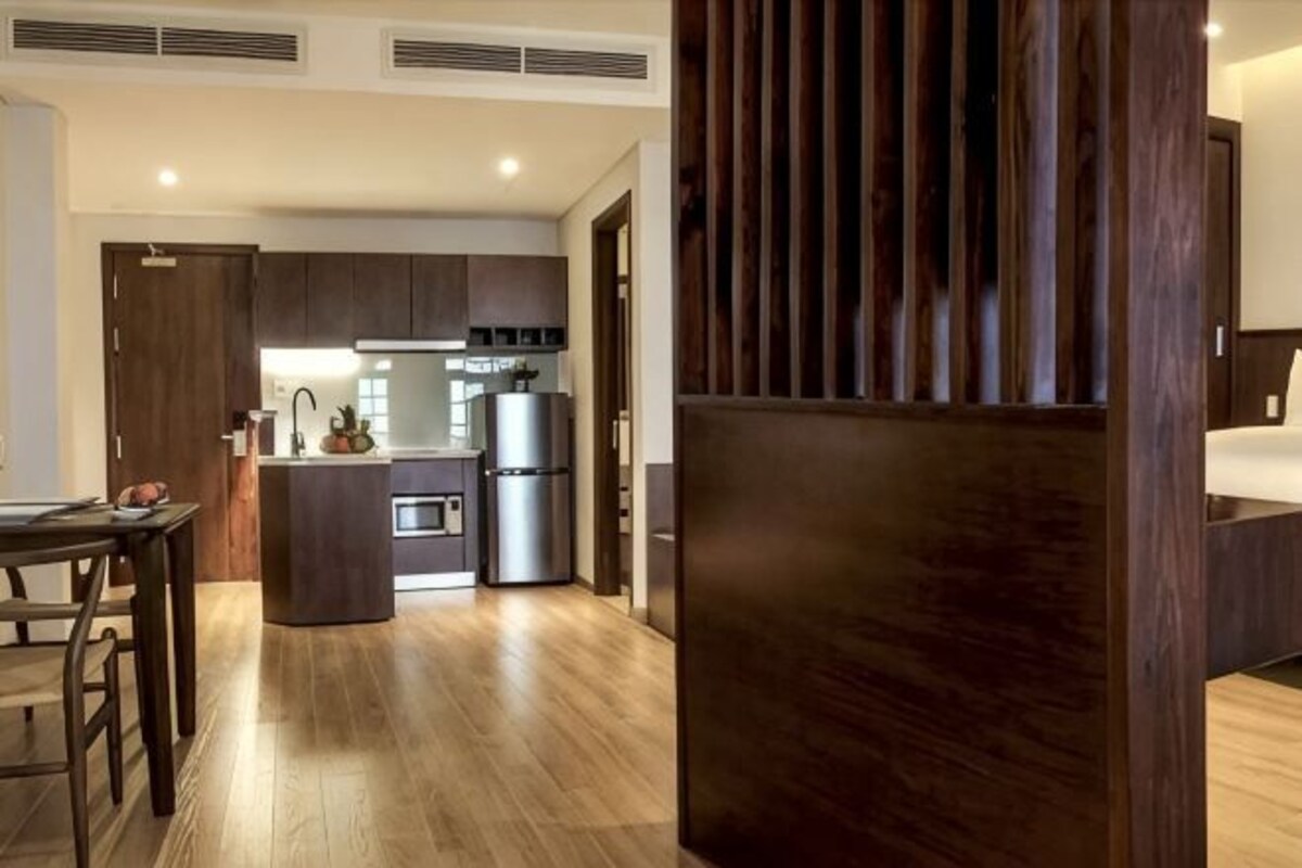 A modern kitchen with a central island, built-in appliances, and a dining area with a wooden table.