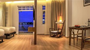 A hotel room with two beds, a dining table, and a view of the city at night. - Di lusso Boutique Hotel Riverside Danang (Da Nang)