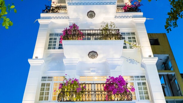 The exterior of the Di Luesso Hotel with a balcony adorned with flowers and string lights. - Di lusso Boutique Hotel Riverside Danang (Da Nang)