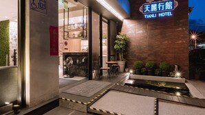 The exterior of Tianli Hotel with a visible entrance, a small outdoor seating area, and a water feature. - Tianli Hotel (Tainan)