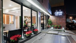 A hotel entrance with a reception desk, seating area, and potted plants. - Tianli Hotel (Tainan)