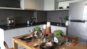 A modern kitchen with a wooden dining table set for four, equipped with wine glasses, plates, and cutlery.